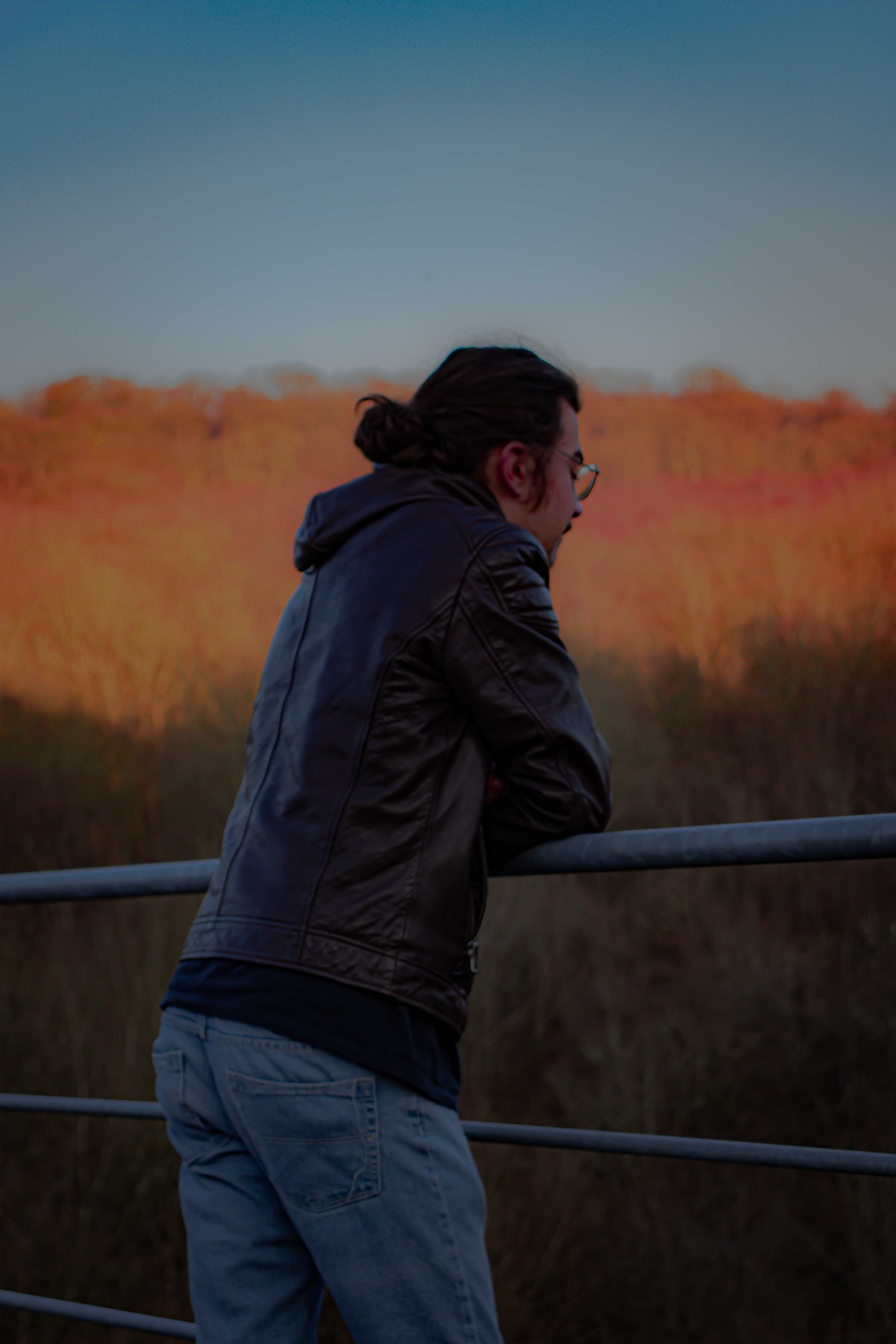 Photo d'un jeune homme ayant les bras posé sur une rambarde en métal